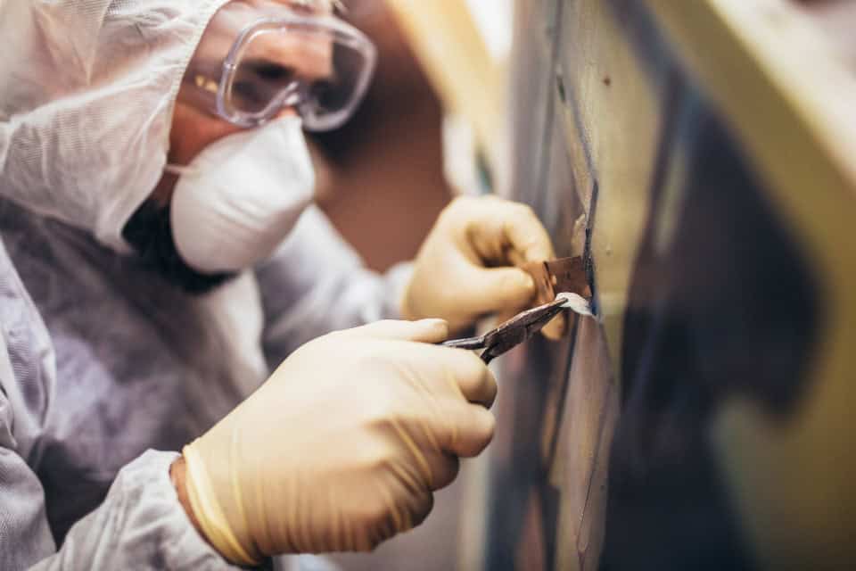 Restoration worker in protective suit, gloves, and goggles using tools during a cleanup job in Chicago